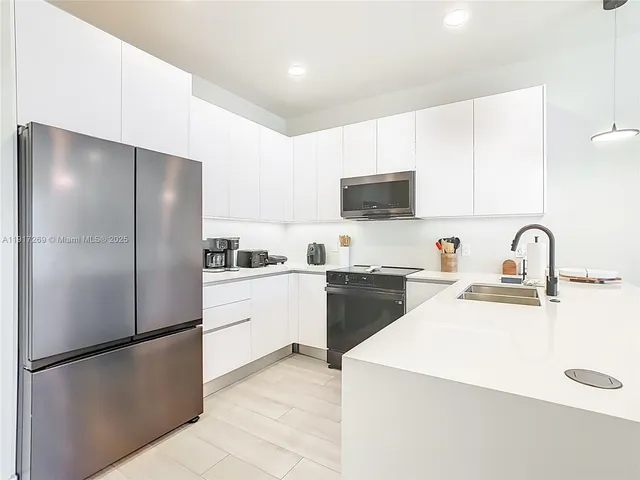 a kitchen with a refrigerator sink and white cabinets