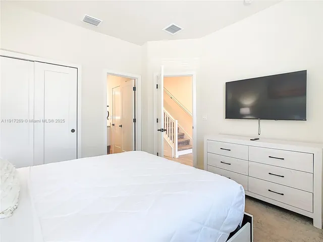 a bedroom with a bed and a flat screen tv in white bedroom
