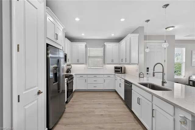 a large kitchen with stainless steel appliances lots of white cabinets and a refrigerator