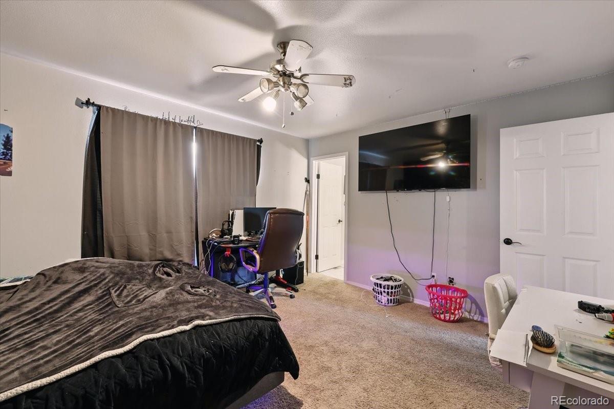 17435 Wagon Train Loop Peyton, CO 80831 - Photo 30 of 40 a bedroom with a bed and a flat screen tv