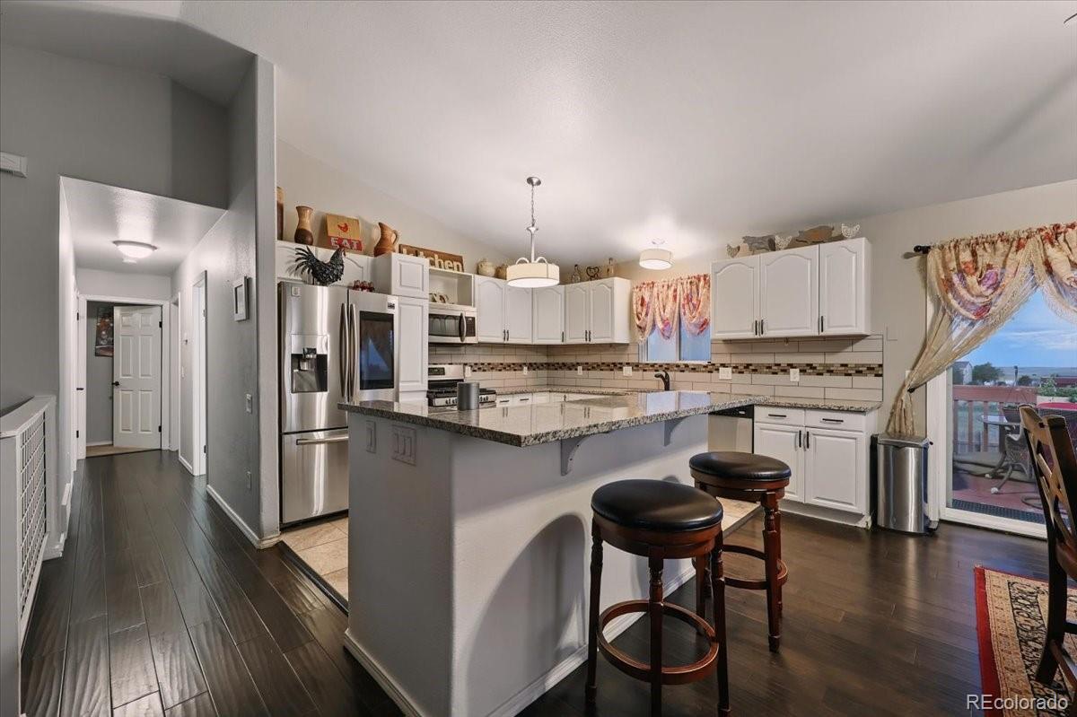 17435 Wagon Train Loop Peyton, CO 80831 - Photo 5 of 40 a kitchen with stainless steel appliances granite countertop a stove refrigerator and a chairs with wooden floor