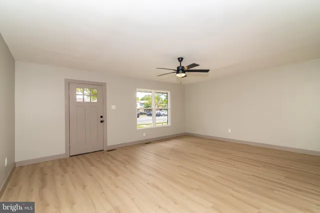 a view of an empty room with window and wooden floor