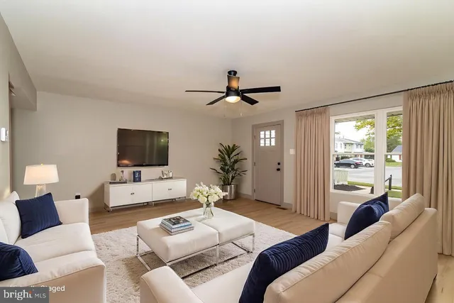 a living room with furniture a flat screen tv and a large window