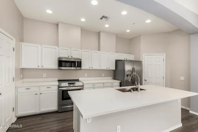 a kitchen with kitchen island a sink stainless steel appliances and cabinets