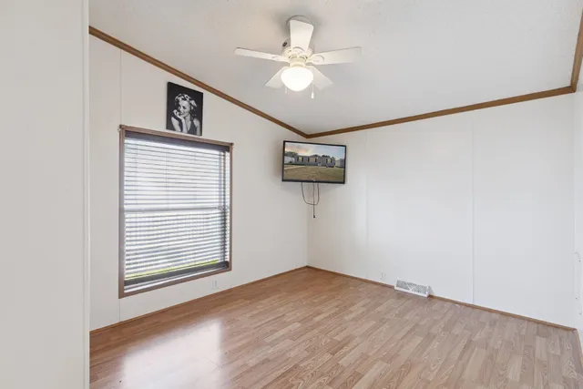 an empty room with wooden floor and a ceiling fan