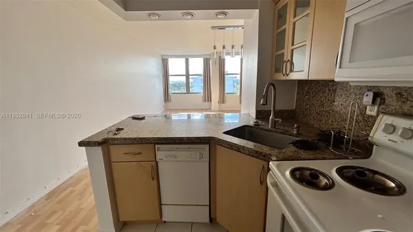 a kitchen with granite countertop a sink a stove and cabinets