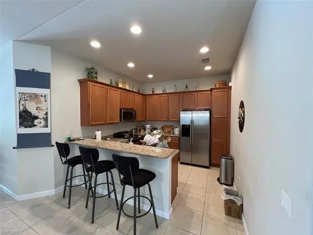 a kitchen with stainless steel appliances kitchen island granite countertop a refrigerator and a sink