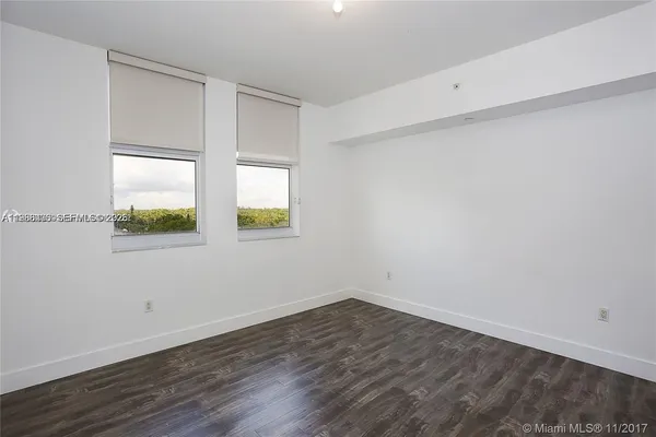 an empty room with wooden floor and window