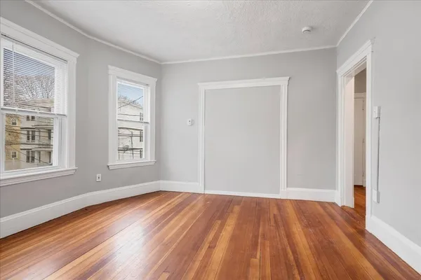 a view of empty room with wooden floor and fan