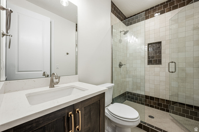 684 West High Tide Place, Unit 131 St. George, UT 84790 - Photo 10 of 27 Spacious bathroom featuring a dark wood-finish vanity with gold-tone hardware, a white countertop, and an undermount sink