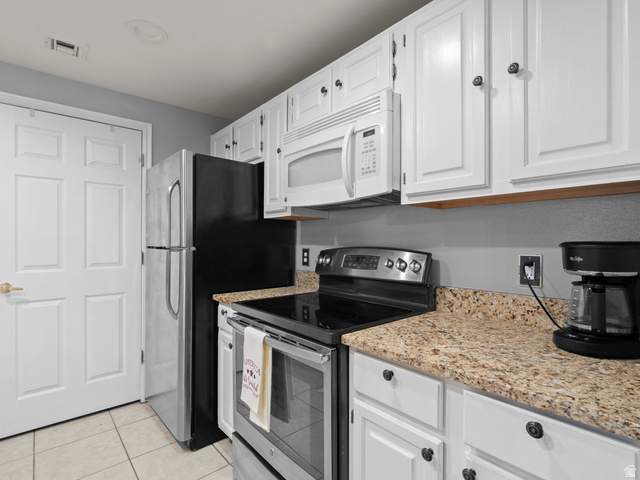 900 Bitner Road, Unit D 34 Park City, UT 84098 - Photo 10 of 25 Kitchen featuring stainless steel electric range oven, white microwave, white cabinets, light stone countertops, and light tile patterned floors