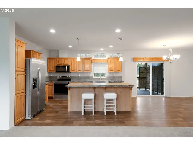 a kitchen with stainless steel appliances granite countertop a sink a refrigerator and a stove