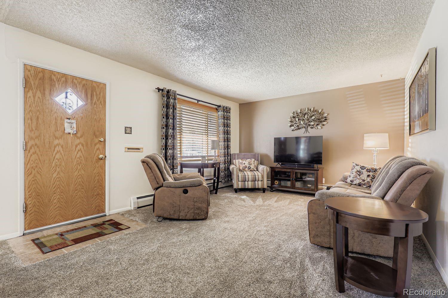 5441 East 67th Place Commerce City, CO 80022 - Photo 5 of 19 a living room with furniture a large window and a flat screen tv
