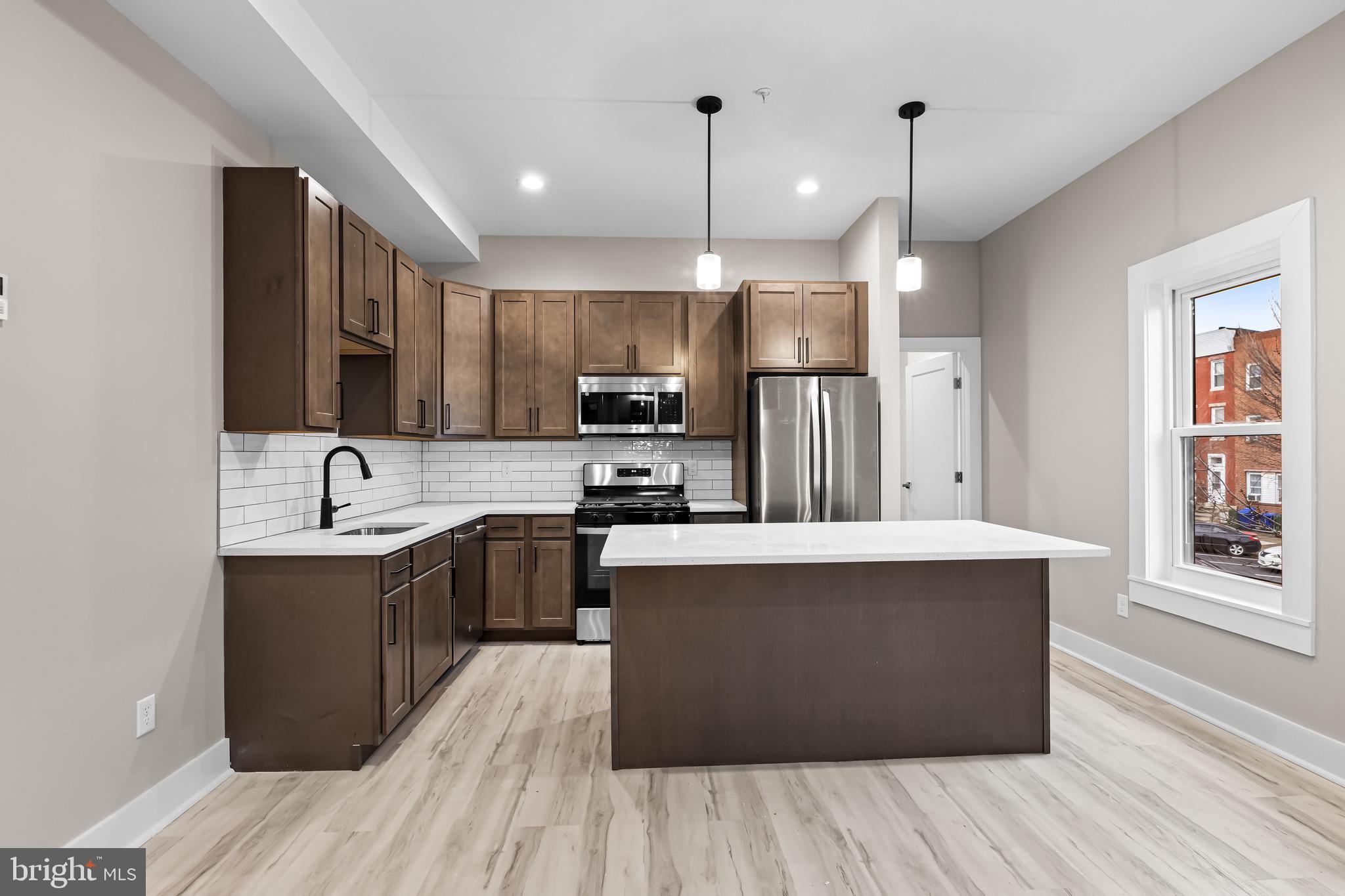 400 South Conkling Street, Unit 2 Baltimore, MD 21224 - Photo 8 of 17 a view of kitchen with stainless steel appliances granite countertop a stove top oven a sink dishwasher a refrigerator and cabinets with wooden floor