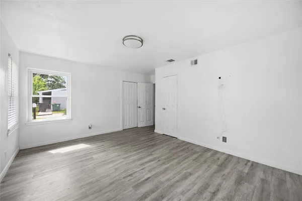 an empty room with wooden floor and windows