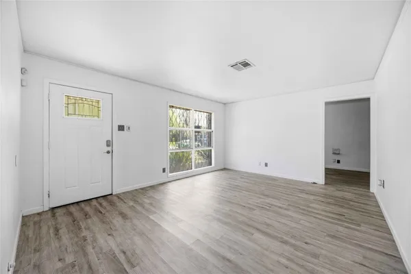 an empty room with wooden floor and windows