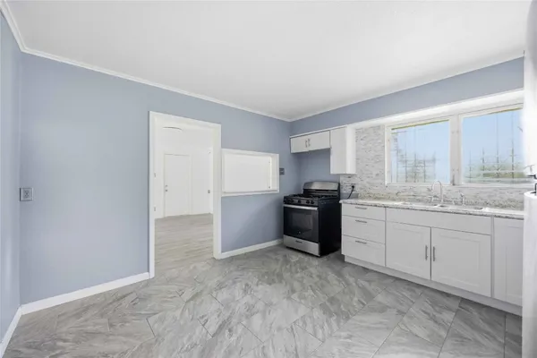 a kitchen with granite countertop a stove a sink and a refrigerator