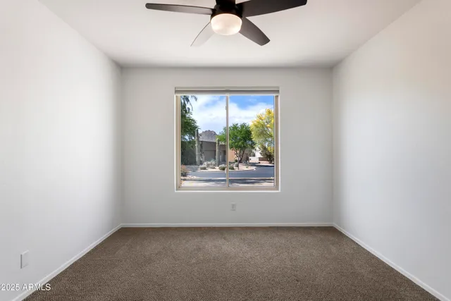 an empty room with a window and a ceiling fan