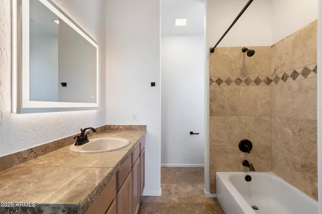 a bathroom with a granite countertop sink a mirror and shower