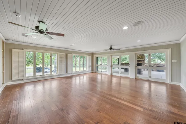 a view of an empty room with a window and wooden floor