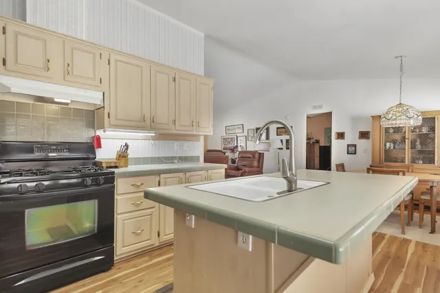 a kitchen with kitchen island a stove a sink dishwasher and white cabinets with wooden floor