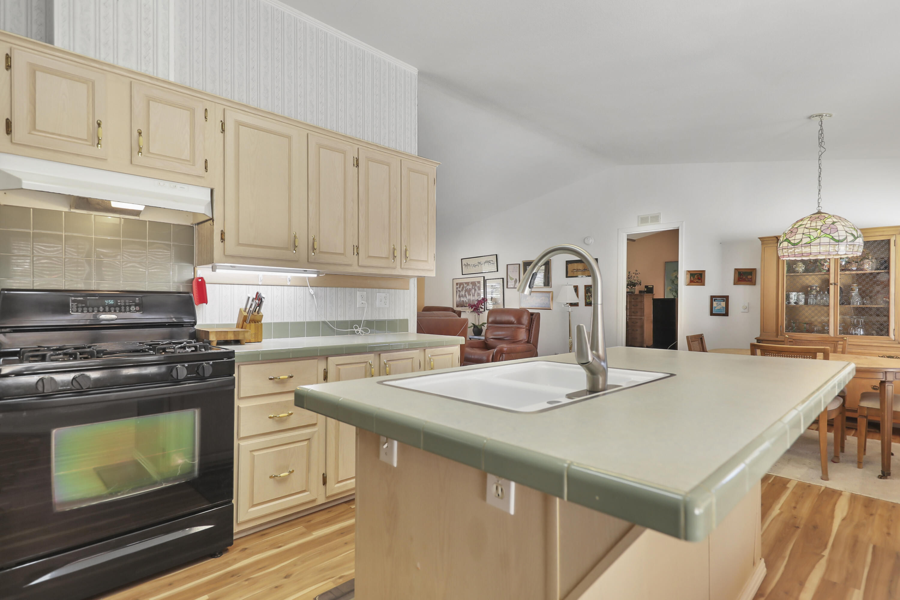 a kitchen with kitchen island a stove a sink dishwasher and white cabinets with wooden floor