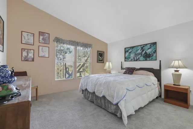 a large bed sitting in a bedroom next to a window with a lamp and a large window