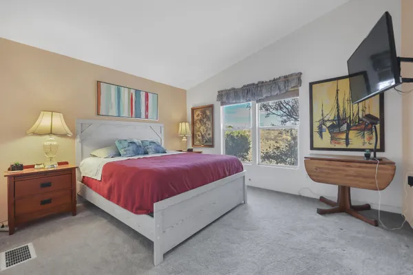 a spacious bedroom with a bed a dresser and a flat screen tv