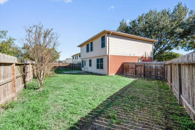 a view of a backyard with wooden fence and large trees