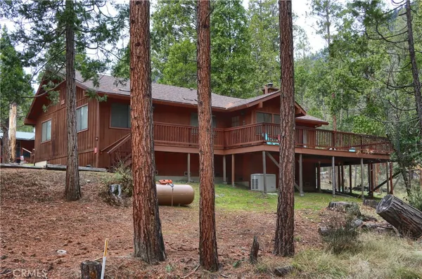 a view of a house with a yard and large tree