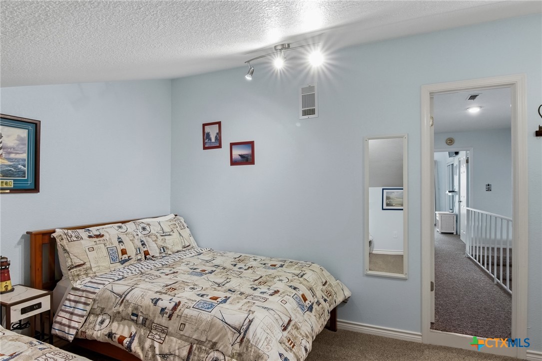 2292 North Fulton Beach Road, Unit 505 Rockport, TX 78382 - Photo 29 of 46 a bedroom with a bed and a chandelier
