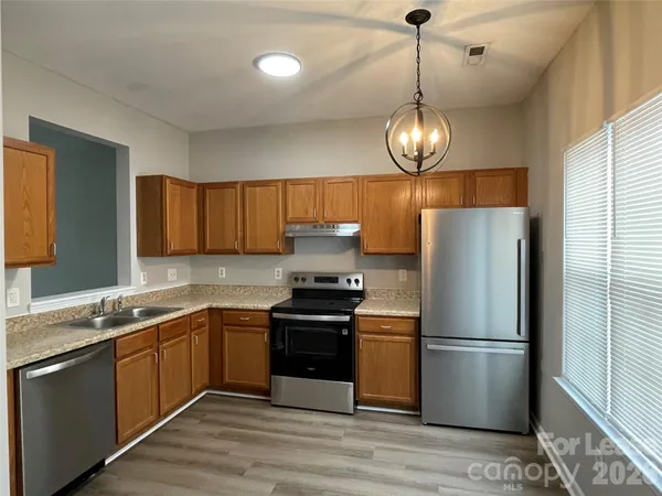 a kitchen with stainless steel appliances granite countertop a stove a refrigerator and a chandelier
