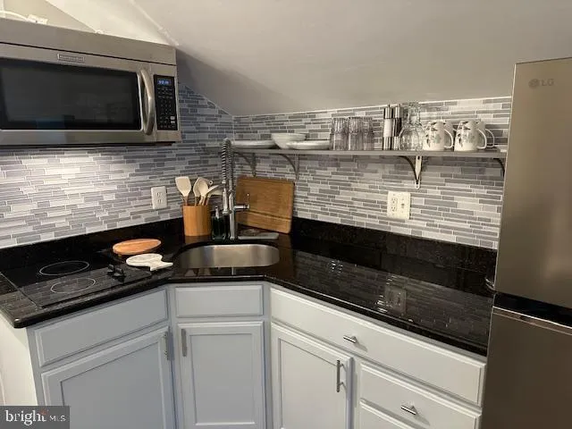 a kitchen with granite countertop stainless steel appliances a stove and a microwave