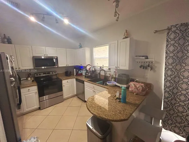 a kitchen with stainless steel appliances granite countertop a sink dishwasher stove refrigerator and cabinets