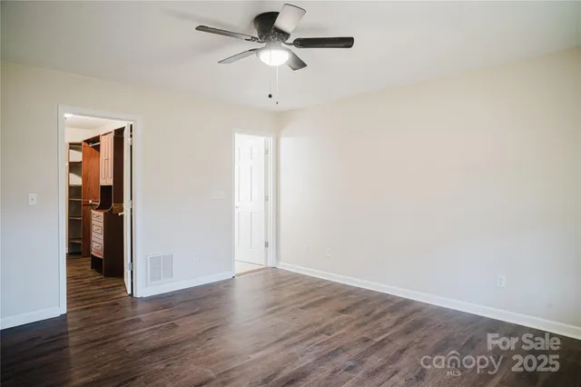 an empty room with wooden floor ceiling fan and windows