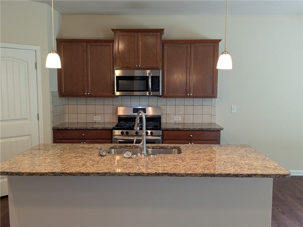 105 Whitney Way Dallas, GA 30157 - Photo 5 of 30 a kitchen with granite countertop a sink a stove and a wooden cabinets