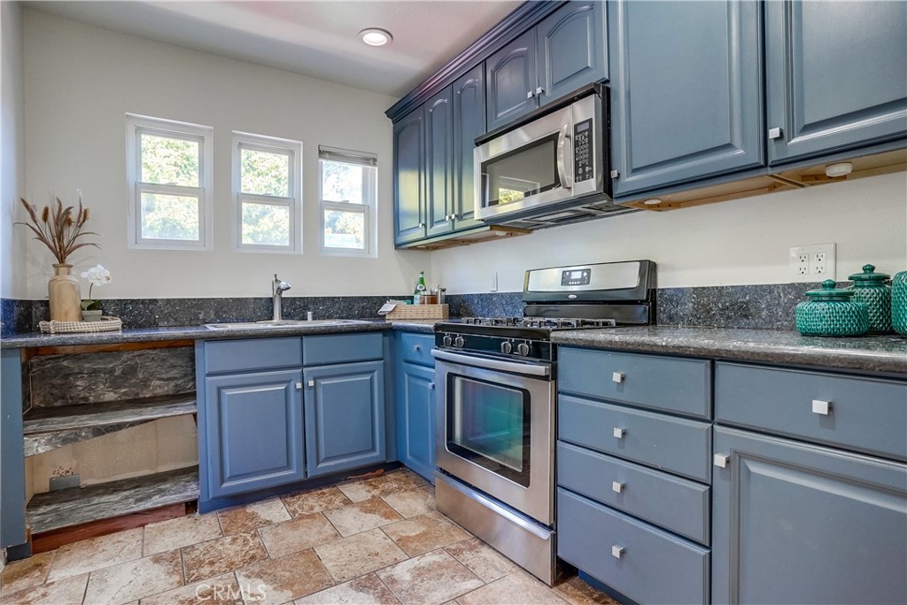 4037 East 7th Street Long Beach, CA 90804 - Photo 7 of 13 a kitchen with granite countertop stainless steel appliances a stove microwave and cabinets