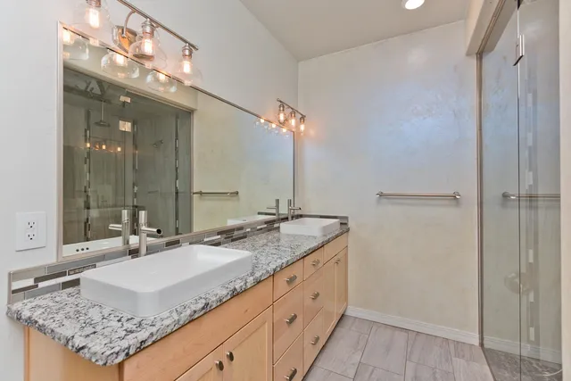 a bathroom with a granite countertop double vanity sink and a mirror