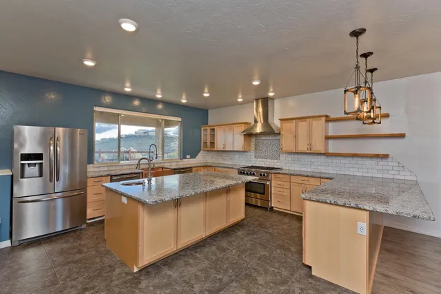 a kitchen with stainless steel appliances granite countertop a sink a stove and a refrigerator