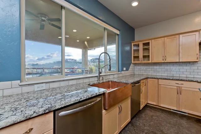 a kitchen with stainless steel appliances granite countertop a sink and a large window