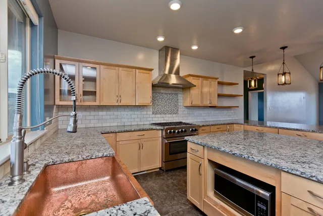 a kitchen with stainless steel appliances granite countertop a stove a sink and a microwave
