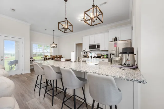 a kitchen with stainless steel appliances granite countertop a kitchen island a stove a table and chairs