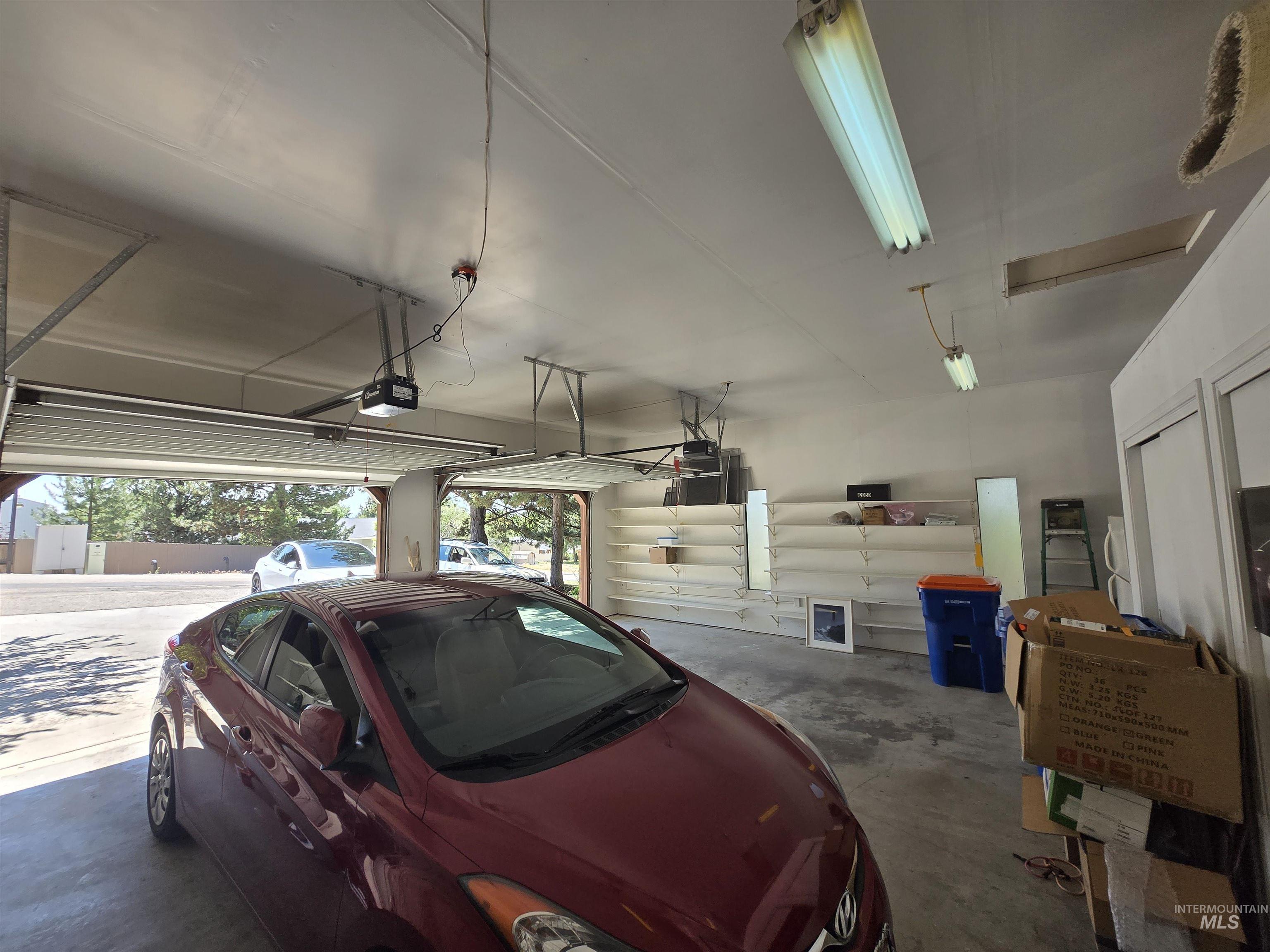 12050 West Hidden Valley Rim Road Boise, ID 83709 - Photo 38 of 39 Two-car garage featuring automatic door openers, fluorescent ceiling lighting, and concrete flooring