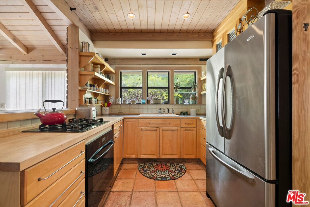 9145 La Tuna Canyon Road Sun Valley, CA 91352 - Photo 9 of 16 a kitchen with stainless steel appliances granite countertop a refrigerator a sink a stove and white cabinets