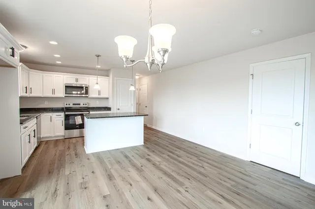 an open kitchen with wooden floor and stainless steel appliances