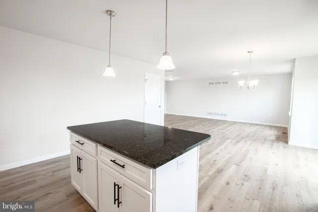 a kitchen with granite countertop a stove a sink and a wooden floor