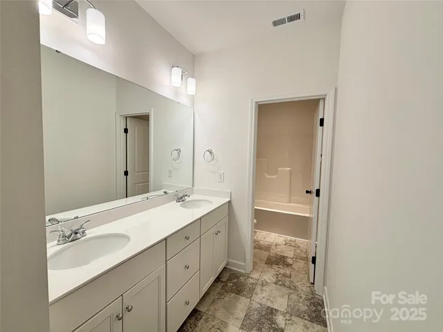 a spacious bathroom with a double vanity sink mirror and shower