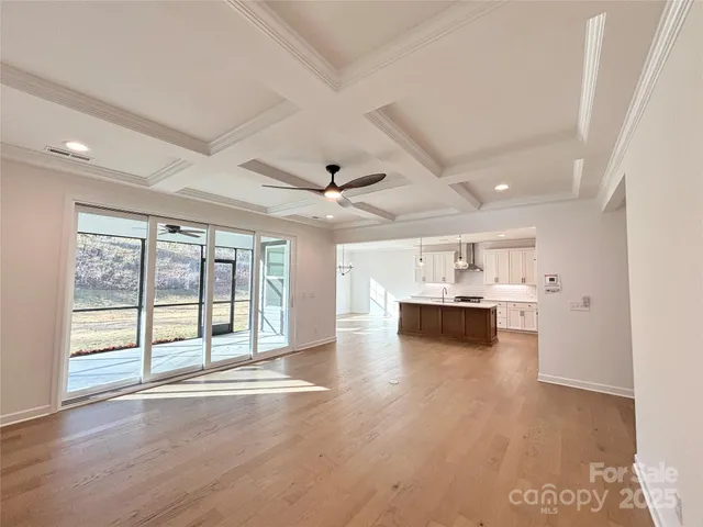 a view of an empty room with a window and kitchen view