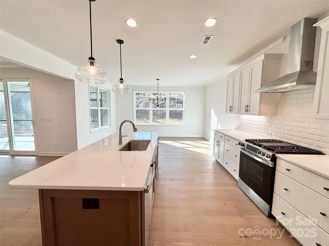 a kitchen with stainless steel appliances granite countertop a sink a stove and a wooden floors