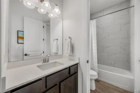 a bathroom with a sink a toilet a mirror and shower